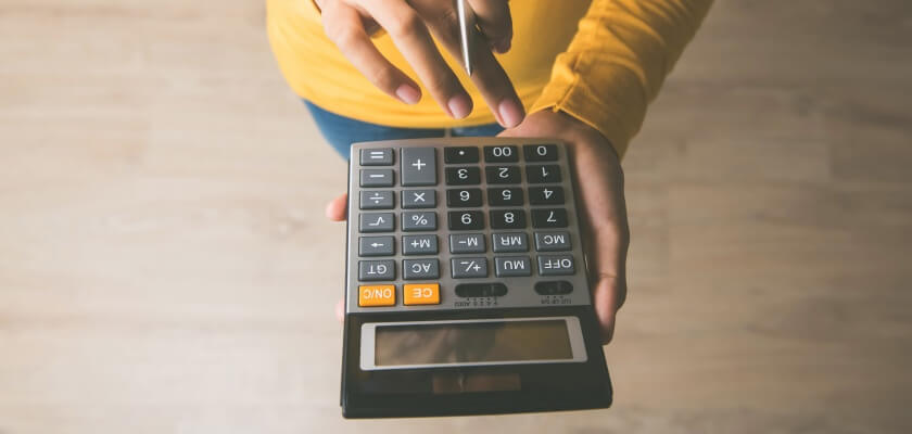 Человек с калькулятором делает расчеты, чтобы сократить ежедневные расходы.