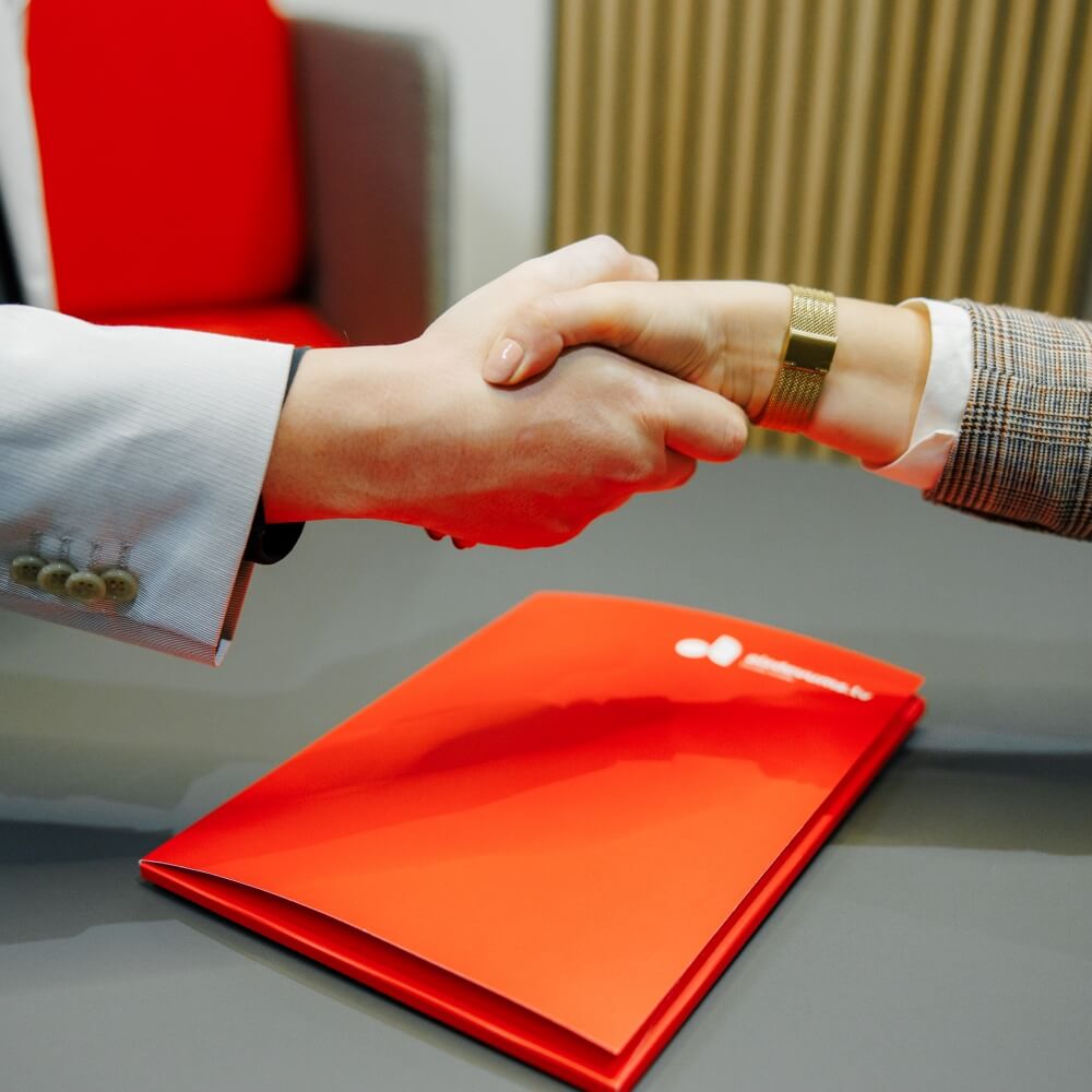 Деловые партнеры пожимают руку сотруднику Aizdevums.lv за заключенный договор.