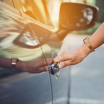 Sieviete taisa vaļā durvis auto kredītā paņemtajai automašīnai.