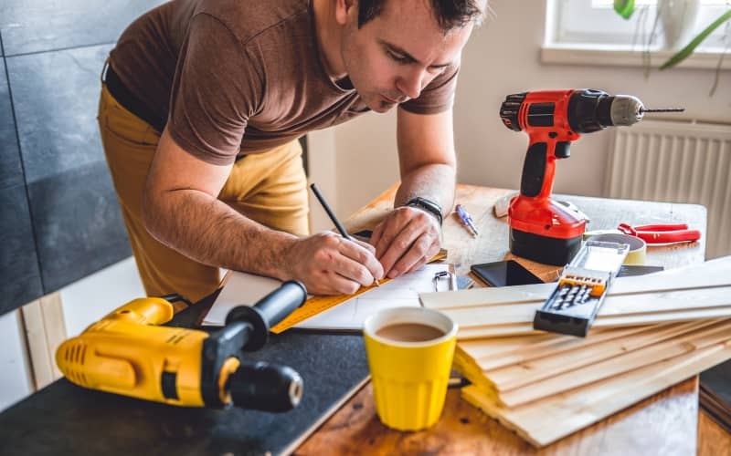 Мужчина делает ремонт дома сам, чтобы сэкономить деньги.