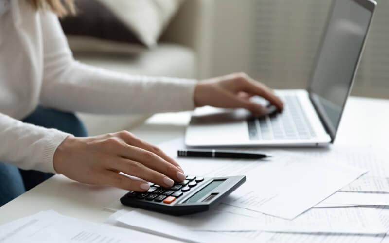 Sieviete ar kalkulatoru aprēķina finansiālo ieguvumu izvēloties pārkreditāciju