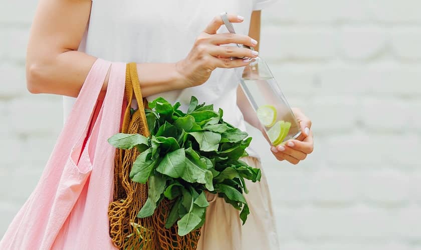 Женщина с собственным пакетиком zero waste и бутылкой воды.